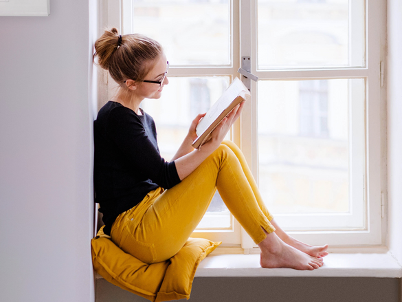 Frau lesend vor Fenster