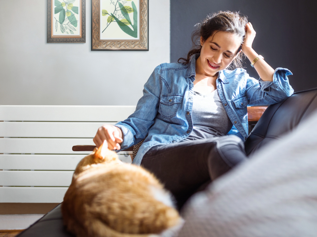 Zehnder_RAD_NovaNEO_Relax-HG.tif Beautiful young woman relaxing on sofa with her cat in living room.