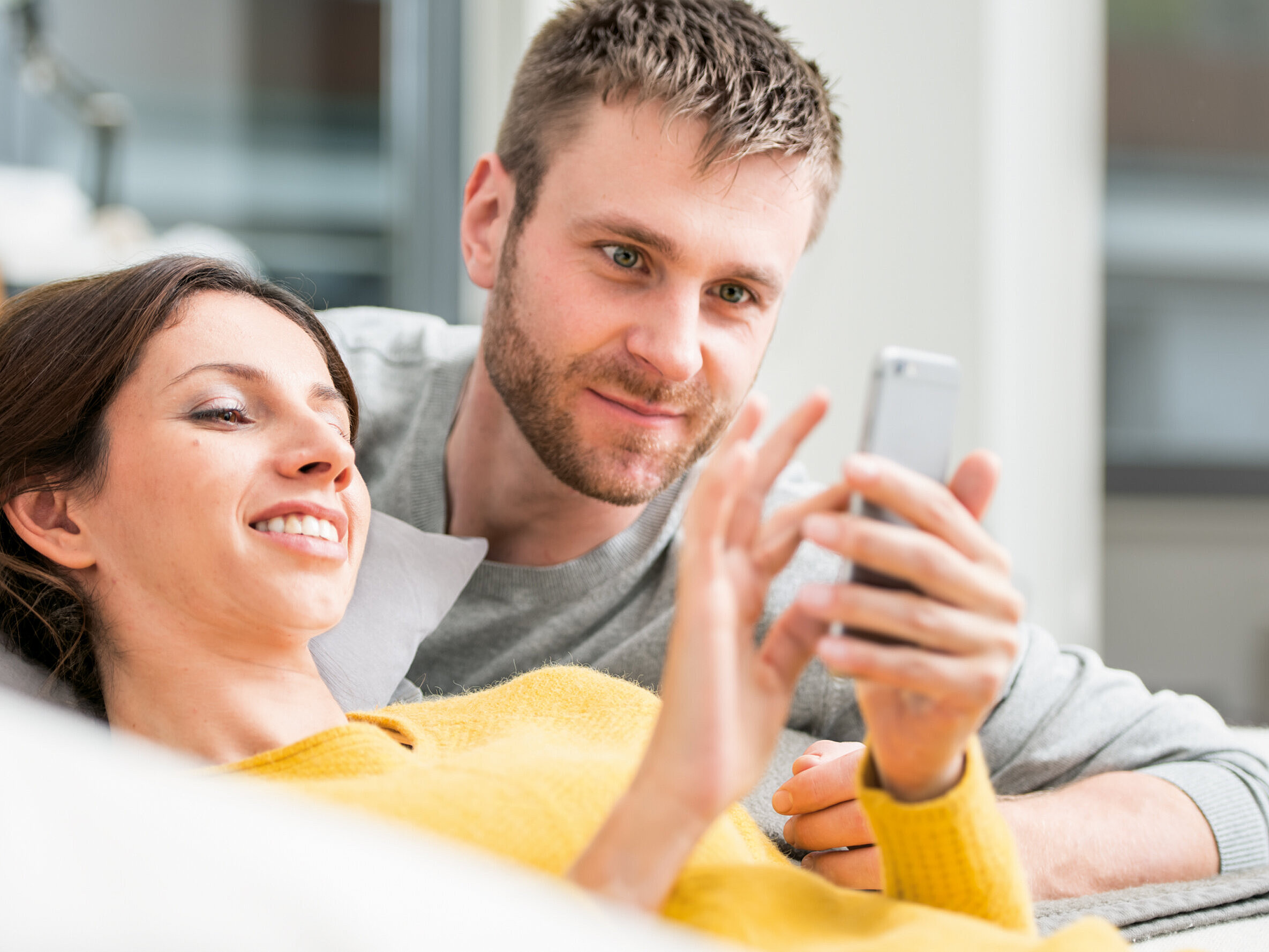 Régulation de l’air ambiant par smartphone femme allongée sur le canapé regarde le smartphone
